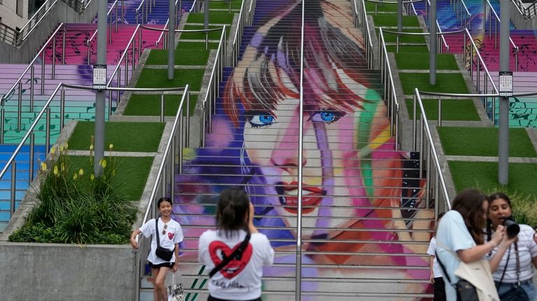 Fans pose by a Taylor Swift portrait painted on a...