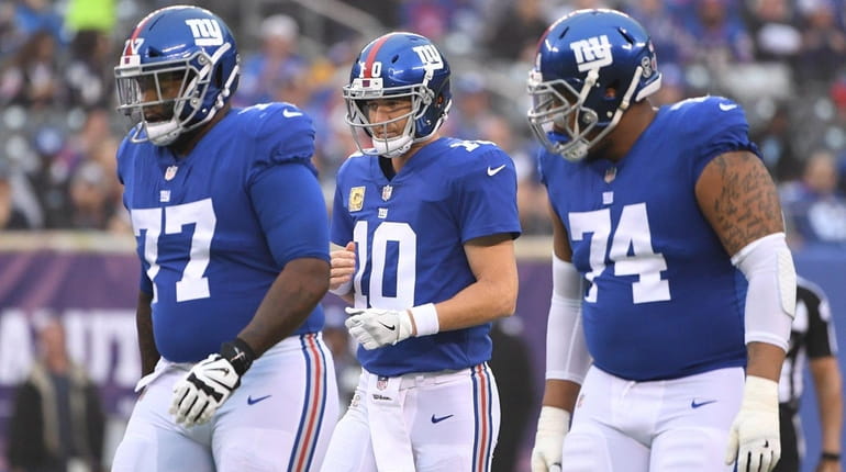 Giants quarterback Eli Manning, center, reacts after he is forced...
