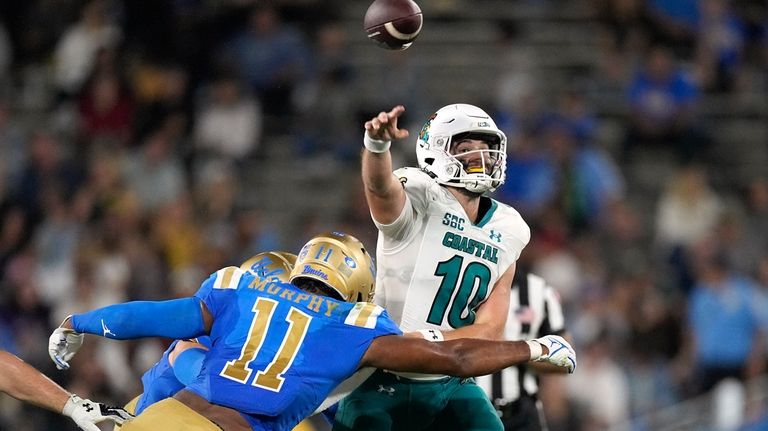 Coastal Carolina quarterback Grayson McCall, right, passes while under pressure...