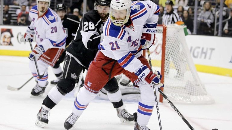 Rangers center Derek Stepan, right, skates around Los Angeles Kings...