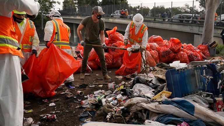 California Gov. Gavin Newsom, center, helps clean a homeless encampment...