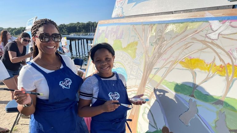 Trina Thomas and her daughter, Zurey, paint a mural panel...