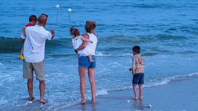 Attendees toss carnations into the ocean after the annual ceremony...