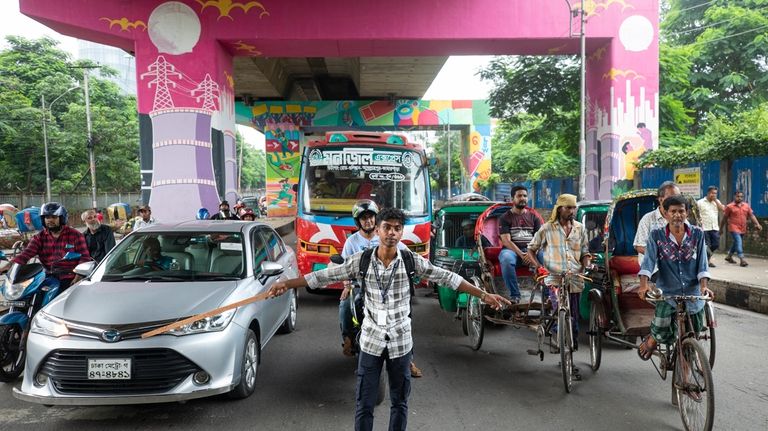 A student directs traffic in Dhaka, Bangladesh, on Aug. 8,...