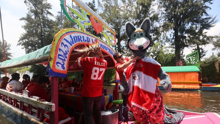 Kansas City Chiefs fans adjust their costumes on "trajinera" boats...