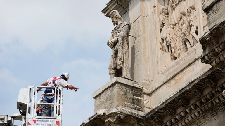 Workers inspect the 315 A.D Arch of Constantine, near the...