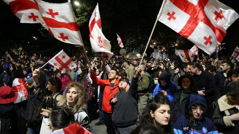 Demonstrators waving Georgian national flags gather in front of the...