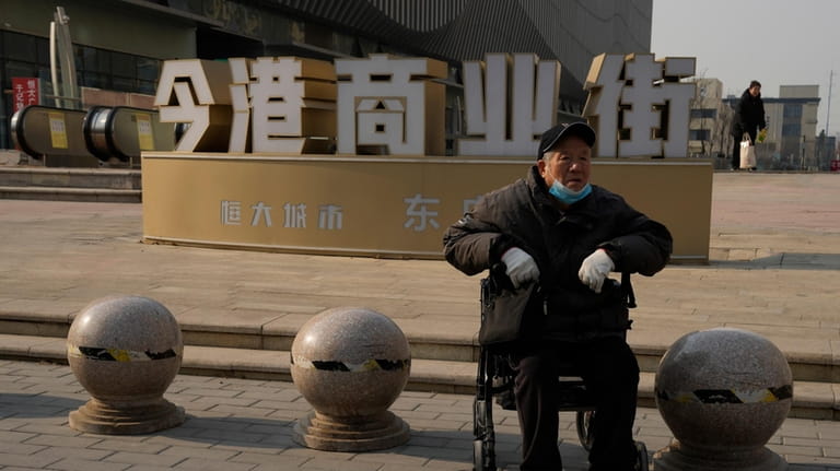 An elderly man sits in a wheelchair near a partially...