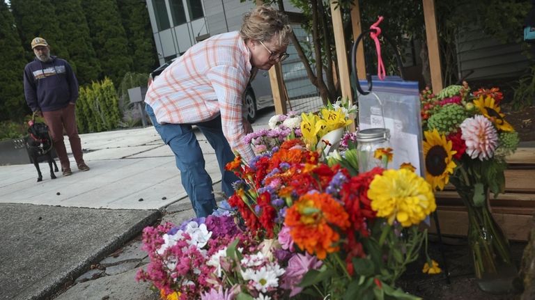 A visitor places flowers on a memorial for a beloved...