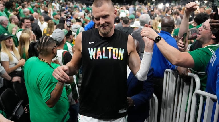 Boston Celtics center Kristaps Porzingis, center, celebrates with fans after...