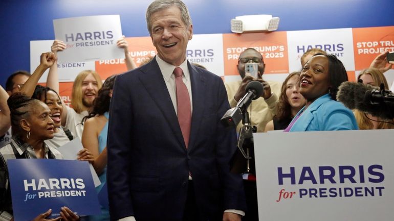 N.C. Governor Roy Cooper smiles as he steps up to...