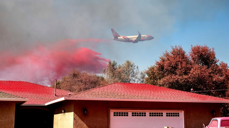 An air tanker drops fire retardant while trying to keep...