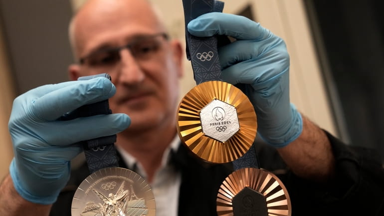 An employee holds medals for the upcoming 2024 Paris Olympic...
