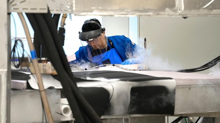 A magnet test engineer checks fluid levels in a testing...