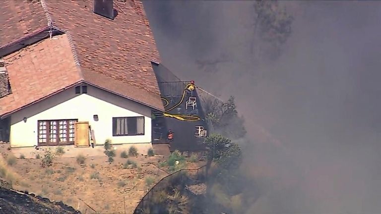 A firefighter sprays water as several homes burn as a...