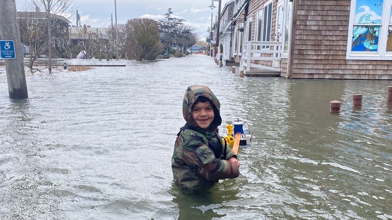 Kai Chenault, 6, pulls a toy boat as he walks...