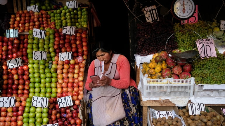 A vendor waits for customers at her produce stand, a...