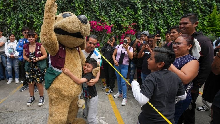 Wisin the “puppy luchador”, is embraced by a child as...