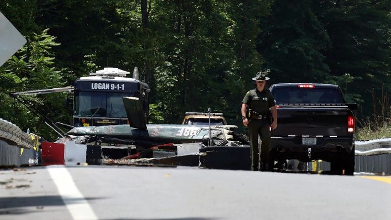 Emergency personnel look over the site of a helicopter that...