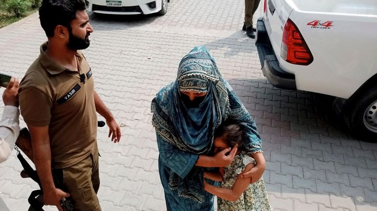 Police officers escort a relative and a child of a...