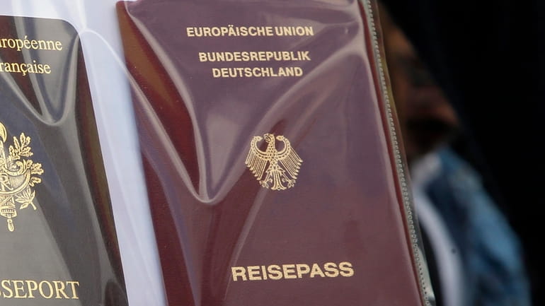 A person holds German and French, left, passports during a...