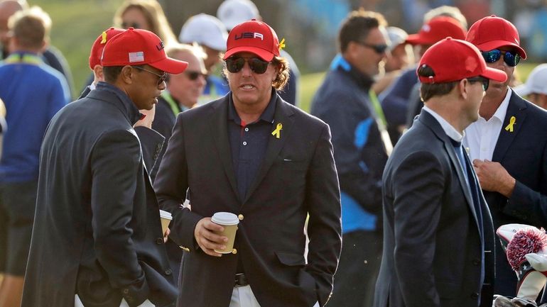 Tiger Woods, left, and Phil Mickelson wait for the closing...