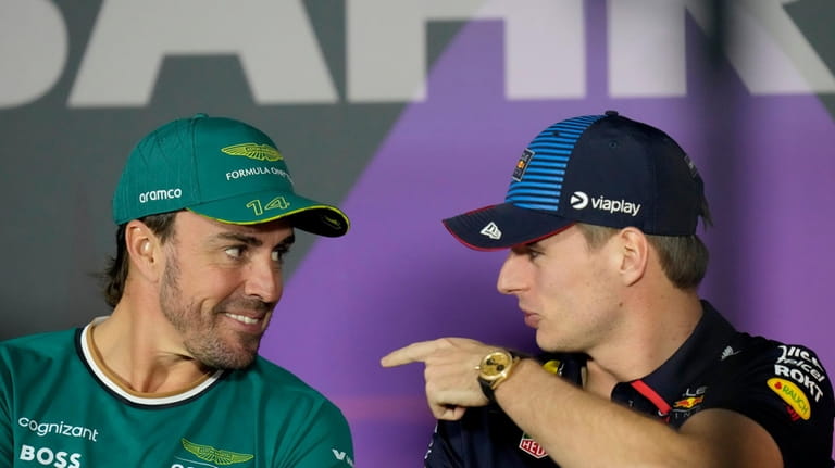 Aston Martin driver Fernando Alonso of Spain, left, speaks with...