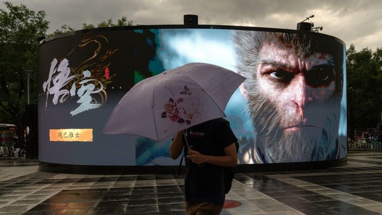 A man holds up an umbrella against the rain as...