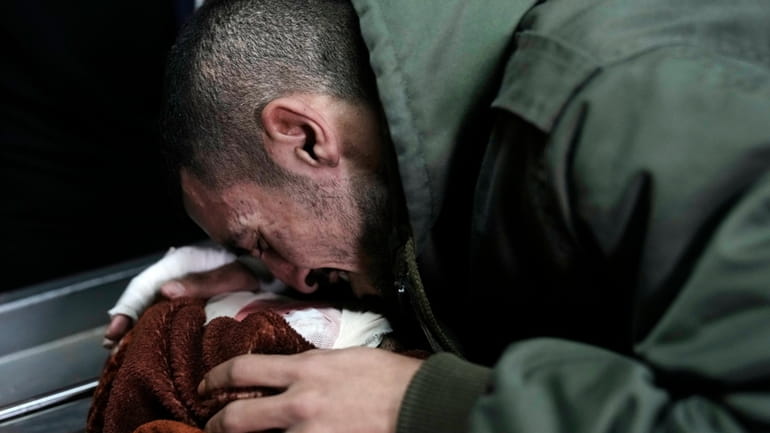 A Palestinian mourner bids farewell to one of three men...