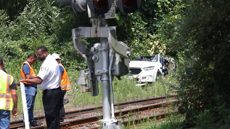 Responders examine the scene where an LIRR train hit a taxi...