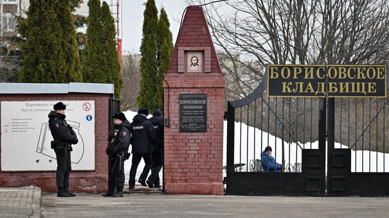 Police officers stand guard at the Borisovskoye Cemetery where the...