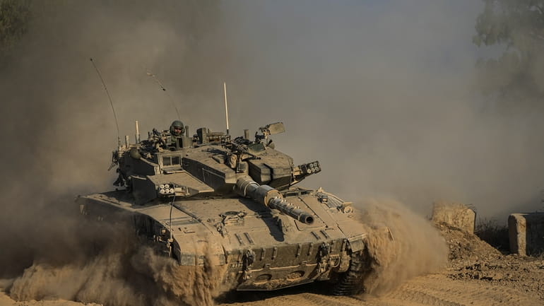 An Israeli soldier moves on the top of a tank...