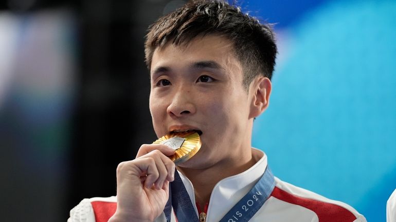 Gold medalist China's Cao Yuan bites his gold medal on...