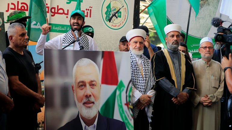 Hamas members attend a protest to condemn the killing of...