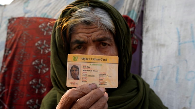 An Afghan refugee show her identity card during a search...