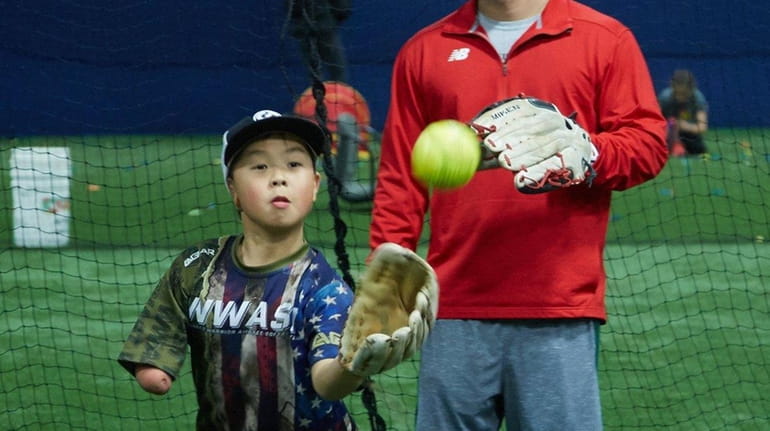 Christian Estes, 9, of Terryville, Connecticut, catches a ball as...