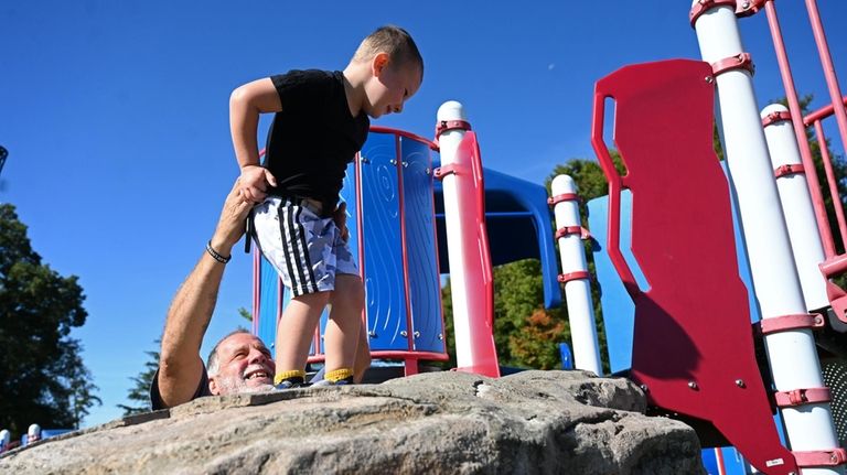 Cameron Scott scales a playground rock at Phelps Lane Park...