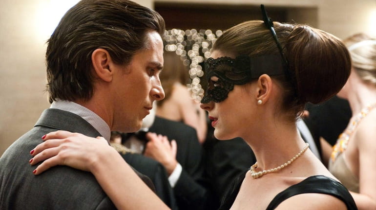 Christian Bale as Bruce Wayne and Anne Hathaway as Selina...
