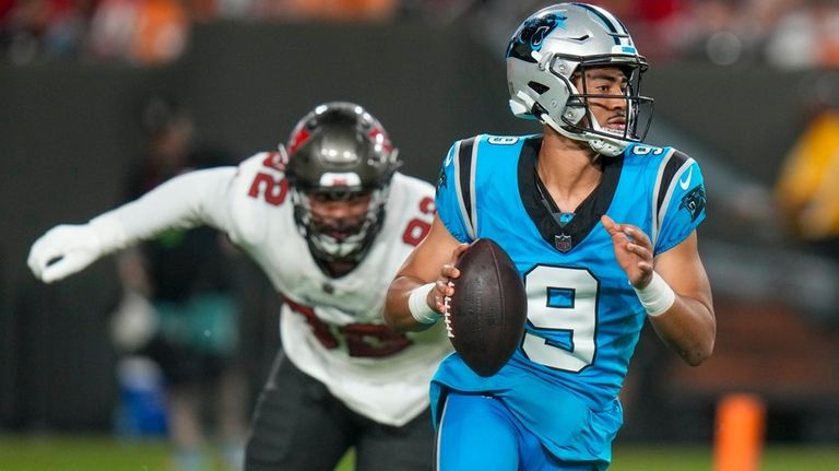 Carolina Panthers quarterback Bryce Young is chased by Tampa Bay...