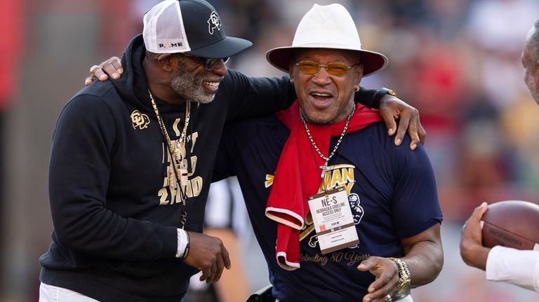 Colorado head coach Deion Sanders, left, talks with former Nebraska...