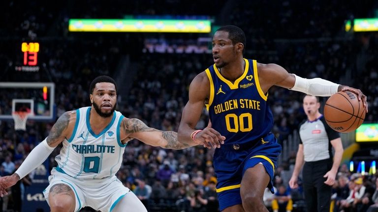 Golden State Warriors forward Jonathan Kuminga, right, is defended by...