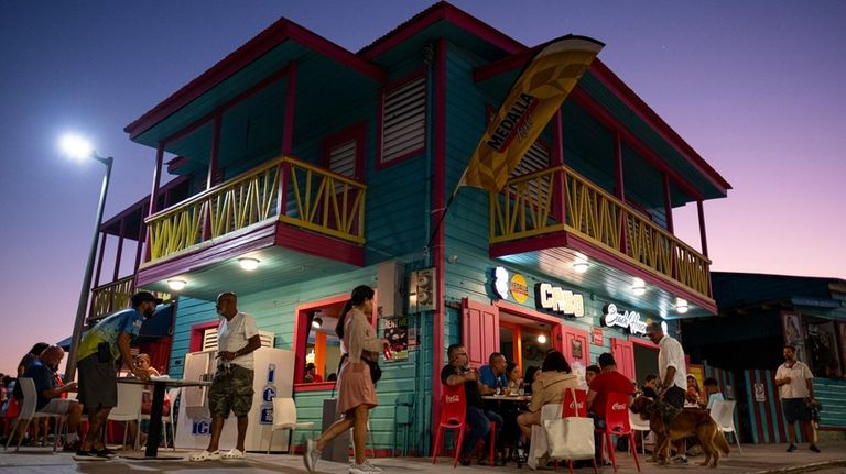 People hang around a local beach bar/restaurant at sunset in...