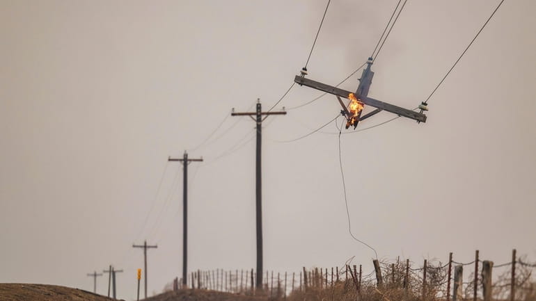 A telephone pole burns from the Smokehouse Creek Fire, Wednesday,...