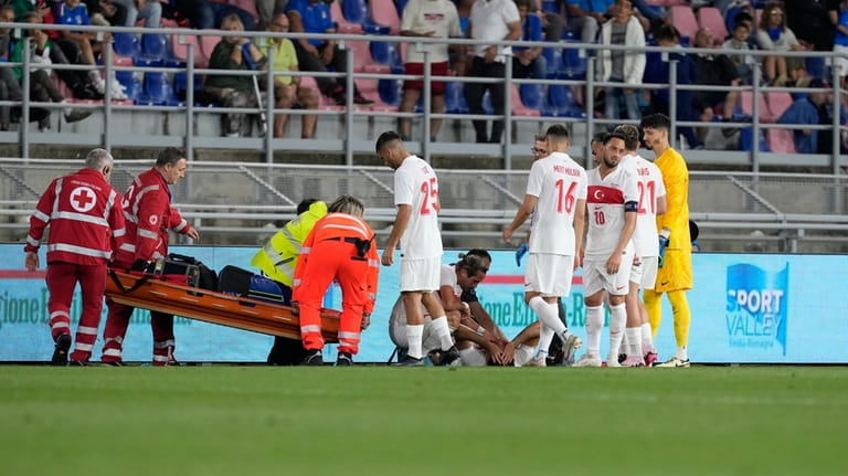 Turkey's Ozan Kabak, bottom, grimaces in pain after being injured...