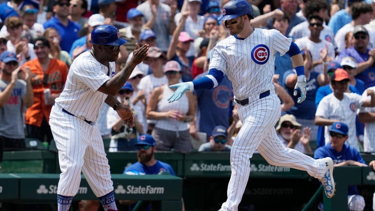 Chicago Cubs' Ian Happ, right, rounds the bases as he...