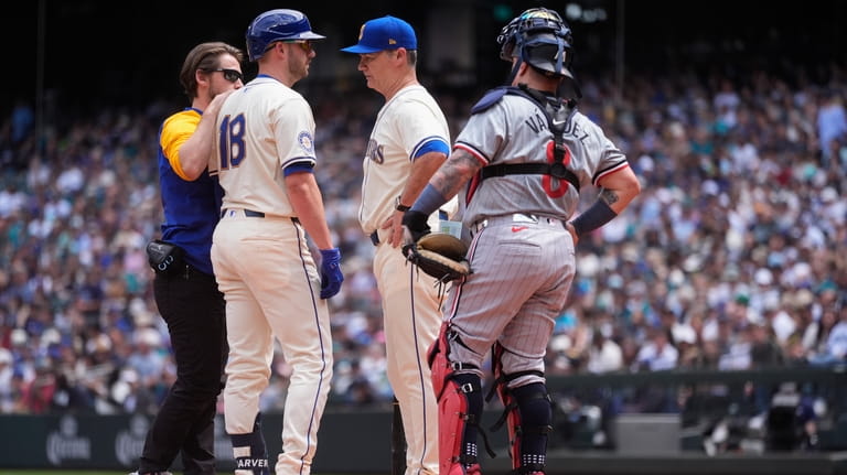 Seattle Mariners catcher Mitch Garver is checked on by a...