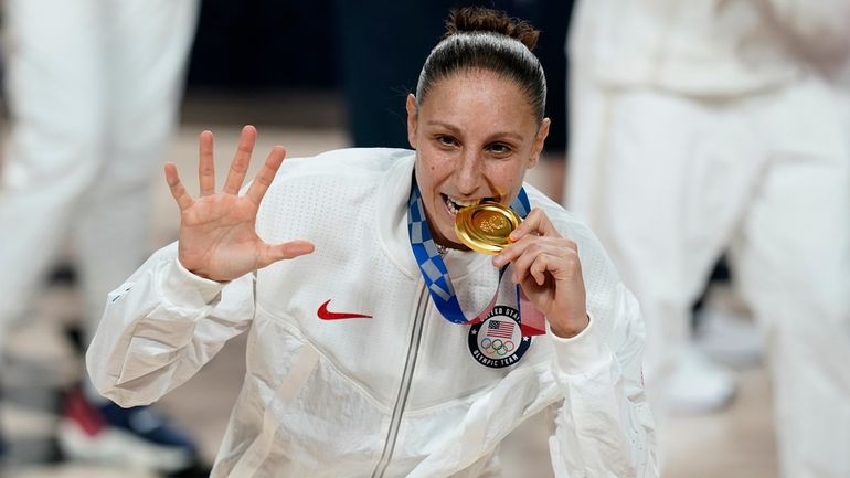 United States's Diana Taurasi bites her gold medal during the...