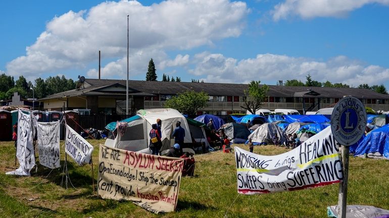 Signs line the front of an encampment of asylum-seekers mostly...