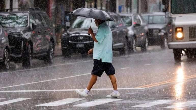 A man uses an umbrella to shield himself from a...