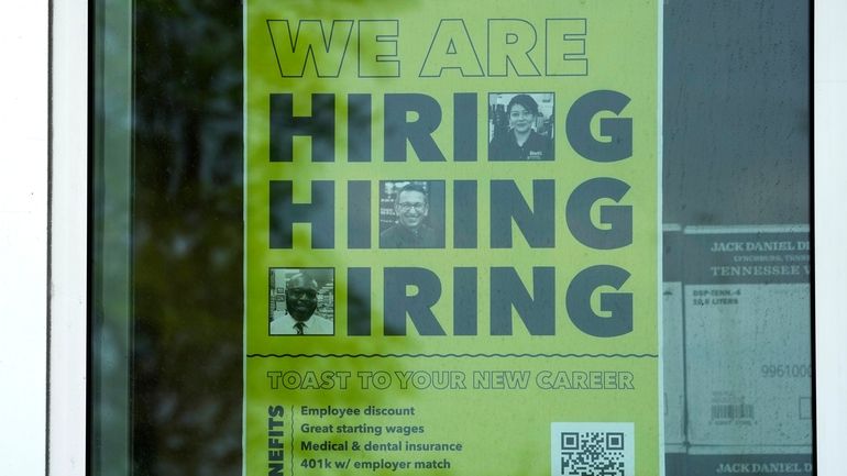 A hiring sign is displayed at a liquor store in...